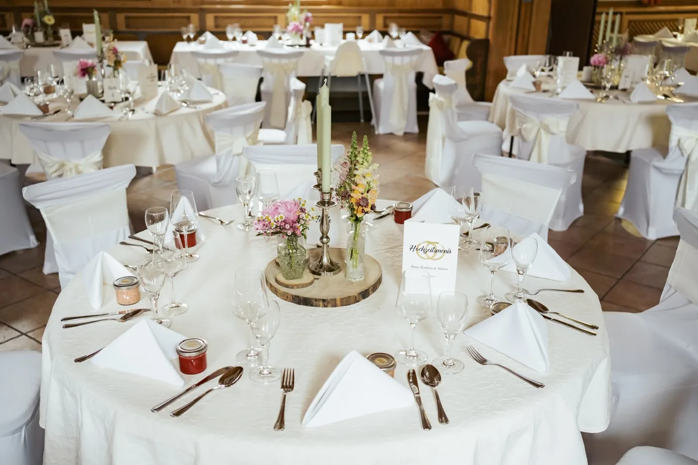 Runde Tische mit weißen Hussen und Blumenschmuck